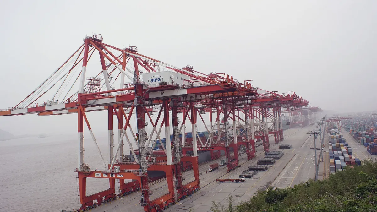 Shipping lithium batteries from China: red ship-to-shore gantry cranes and stacked containers at the Yangshan deep-water terminal in Shanghai